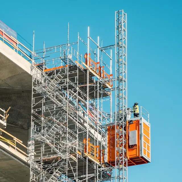 Fassadengerüst der Odendahl GmbH mit orangefarbenem Bauaufzug an einem Bauwerk